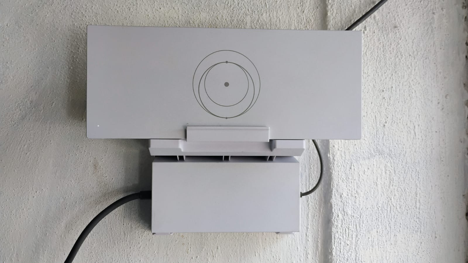 Starlink router and power supply mounted on a wall in a horizontal view.