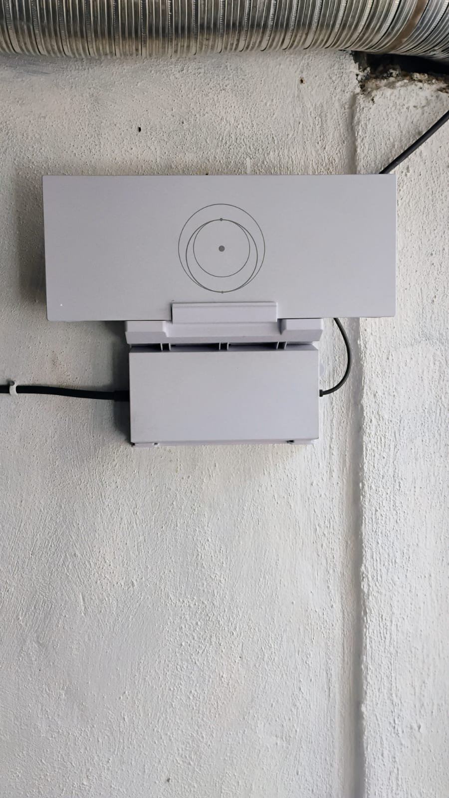 Starlink router and power supply mounted on a white stucco wall.