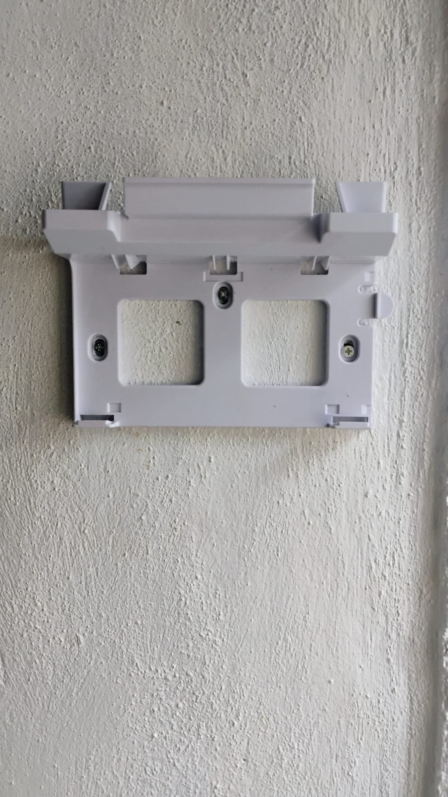 Metal Starlink antenna mount fixed to an exterior wall.
